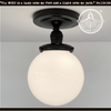 Milk glass globe ceiling light with antique black metal details from The Lamp Goods.