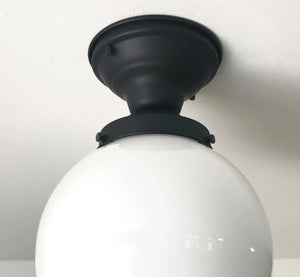 Close-up of a matte black and white globe ceiling fixture installed on a white ceiling.