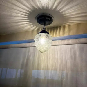 Antique glass ceiling light fixture with chain, illuminating a room.