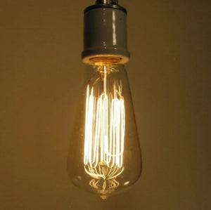 Illuminated 60-watt dimmable bulb with exposed filament, emitting a warm glow.