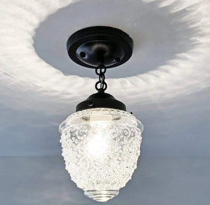 Clear glass ceiling fixture with textured globe shade, black metal accents, and chain hanging from a ceiling mount.