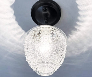 Clear glass ceiling light fixture with textured bubbles, hanging from a black metal canopy.
