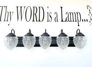 Five-light vanity fixture with clear glass shades and black metal frame; antique style.