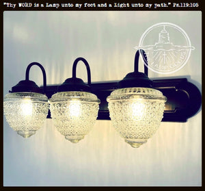 Three-light vanity fixture with antique glass shades and dark bronze finish.