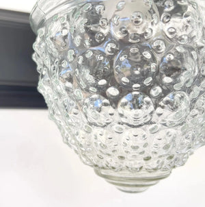 Clear glass vanity light fixture with textured bubbled surface.
