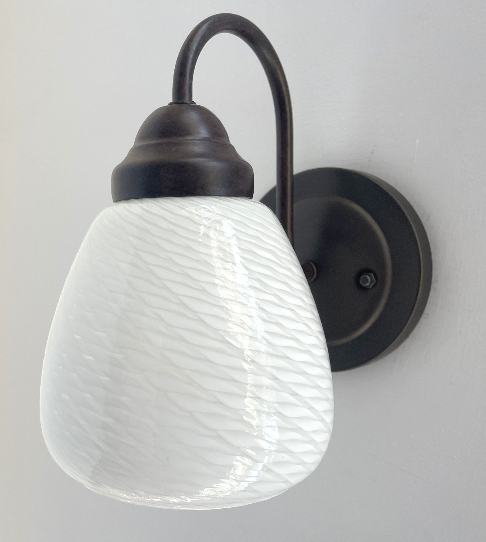 White milk glass wall sconce with a bronze metal arm; textured glass shade.
