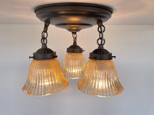 Amber glass ceiling light fixture with hobnail detailing, three lights.
