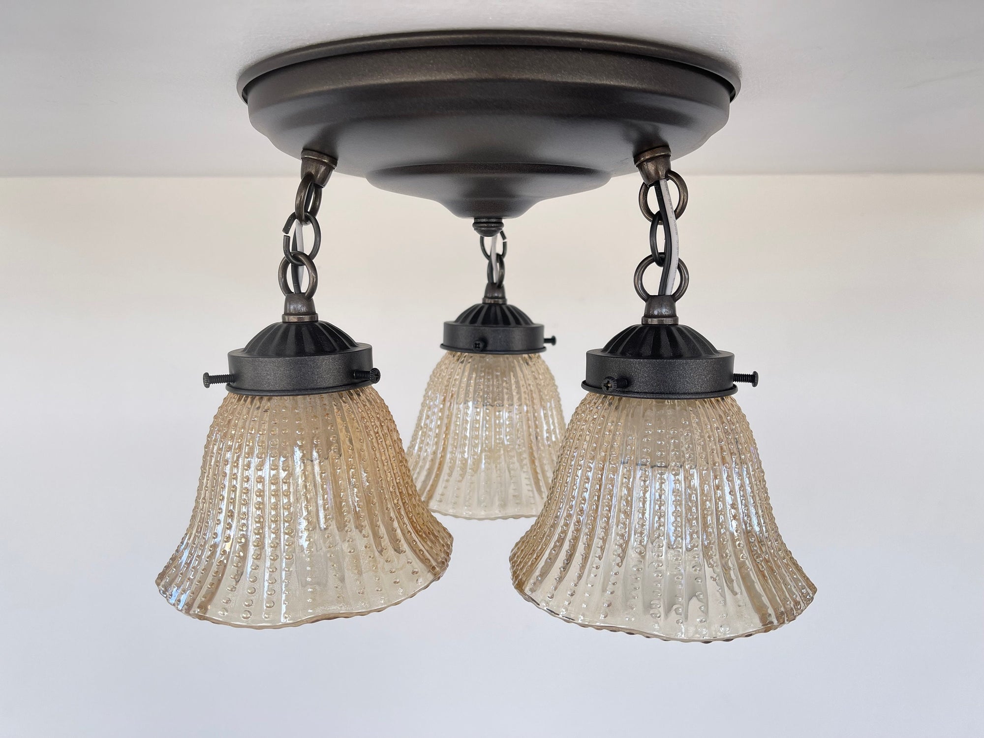 Amber glass ceiling fixture with hobnail detailing, three lights.
