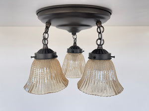 Amber glass ceiling fixture with hobnail detailing, three lights.
