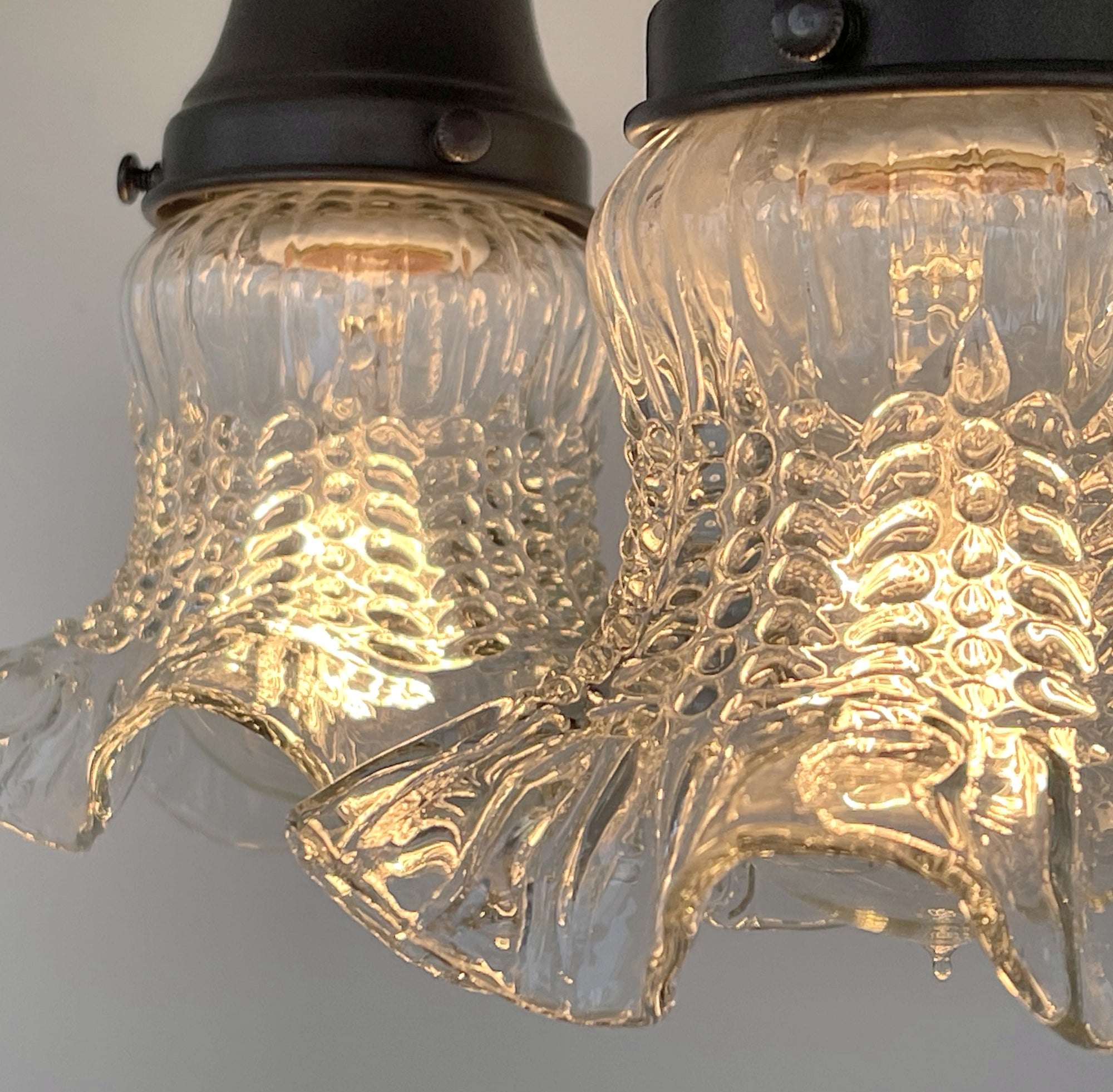 Clear glass hobnail ceiling light fixture, antique 1930s style, illuminated.
