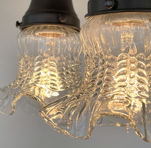 Clear glass hobnail ceiling light fixture, antique 1930s style, illuminated.
