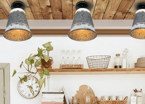 Rustic galvanized metal ceiling lights illuminating a farmhouse kitchen shelf.
