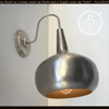 Polished steel modern wall sconce with large, curved shade; The Lamp Goods.

