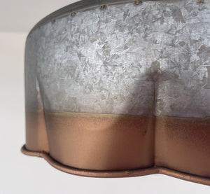 Close-up of a rustic metal ceiling fixture; galvanized steel body with copper-toned bottom.
