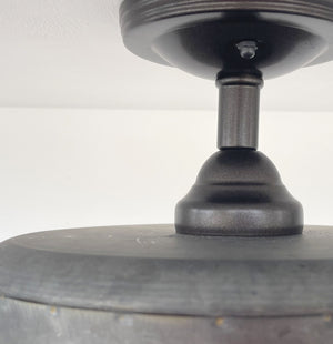 Close-up of dark gray metal ceiling fixture's mounting detail against a white ceiling.

