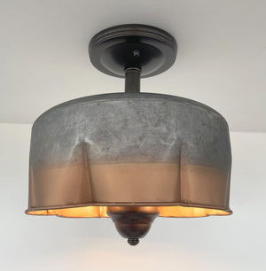 Metal ceiling fixture with copper accents, illuminated against a white wall.
