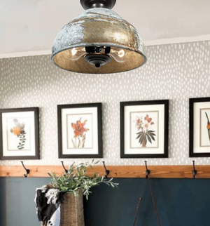 Rustic farmhouse ceiling light fixture, gray metal shade with gold interior, three-bulb design, installed in entryway.
