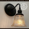 Antique 1930s amber glass hobnail wall sconce with black metal accents.
