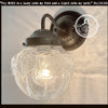Clear glass globe lamp shade with embossed rose pattern, mounted on a dark metal wall sconce.
