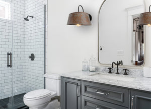 Copper wall sconce with ornate pattern, illuminating a modern bathroom vanity.
