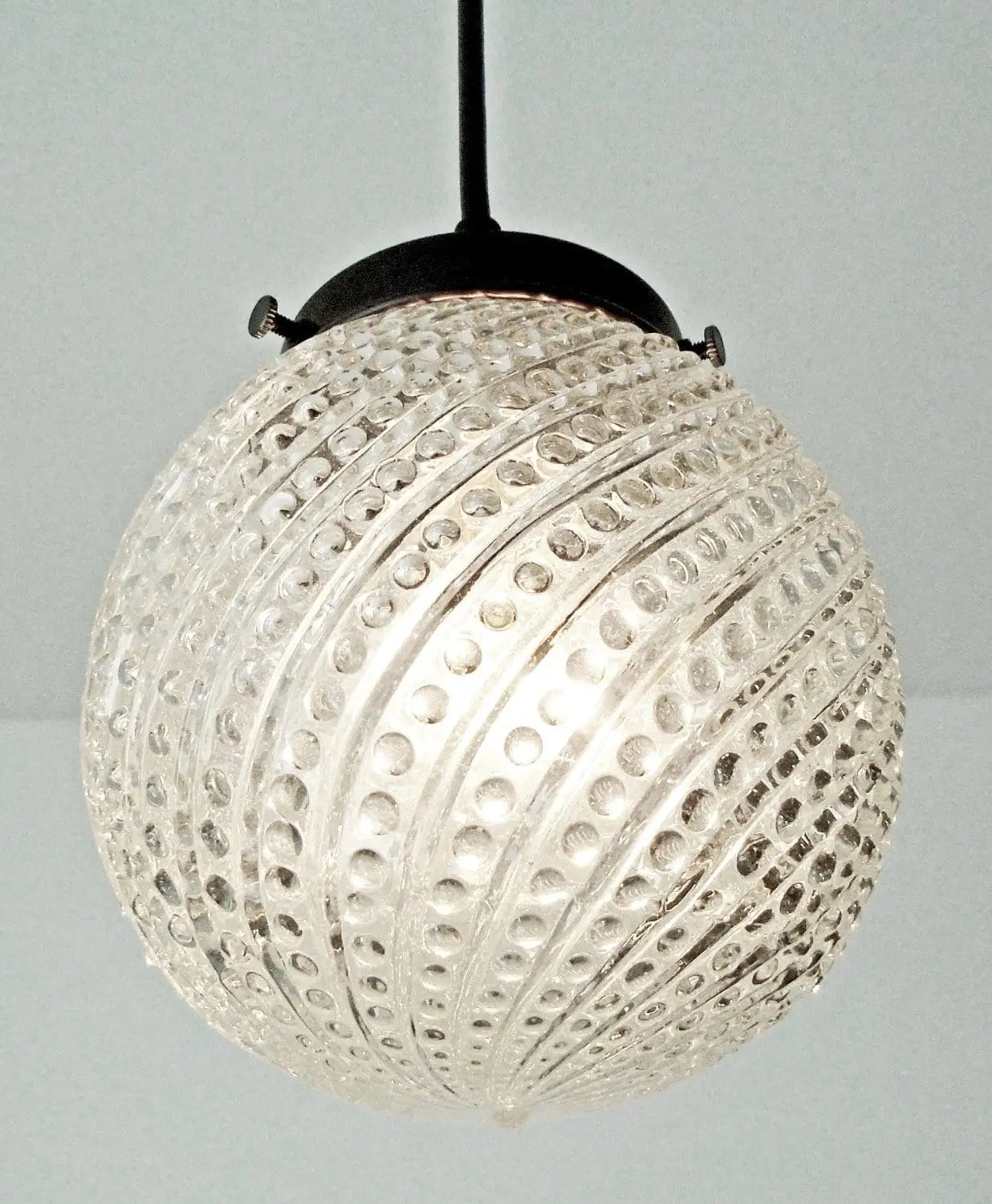 Clear glass pendant light fixture with hobnail swirl pattern.
