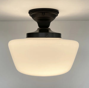 Milk glass ceiling light fixture with dark bronze finish, illuminating a neutral-toned room.
