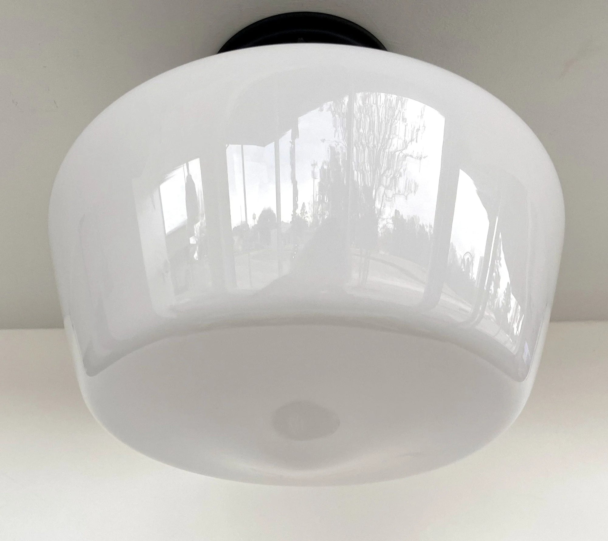 White milk glass ceiling light fixture installed on a white ceiling.
