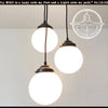 Milk glass chandelier pendant trio with bronze fixtures, perfect for adding a touch of vintage elegance to any space.
