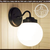 Milk glass globe wall light fixture sconce with black metal arm; The Lamp Goods.

