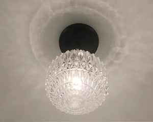 Clear glass ceiling light fixture with a faceted globe shade and black base.
