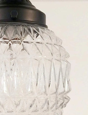 Clear glass pendant light with geometric pattern, bronze fitting.
