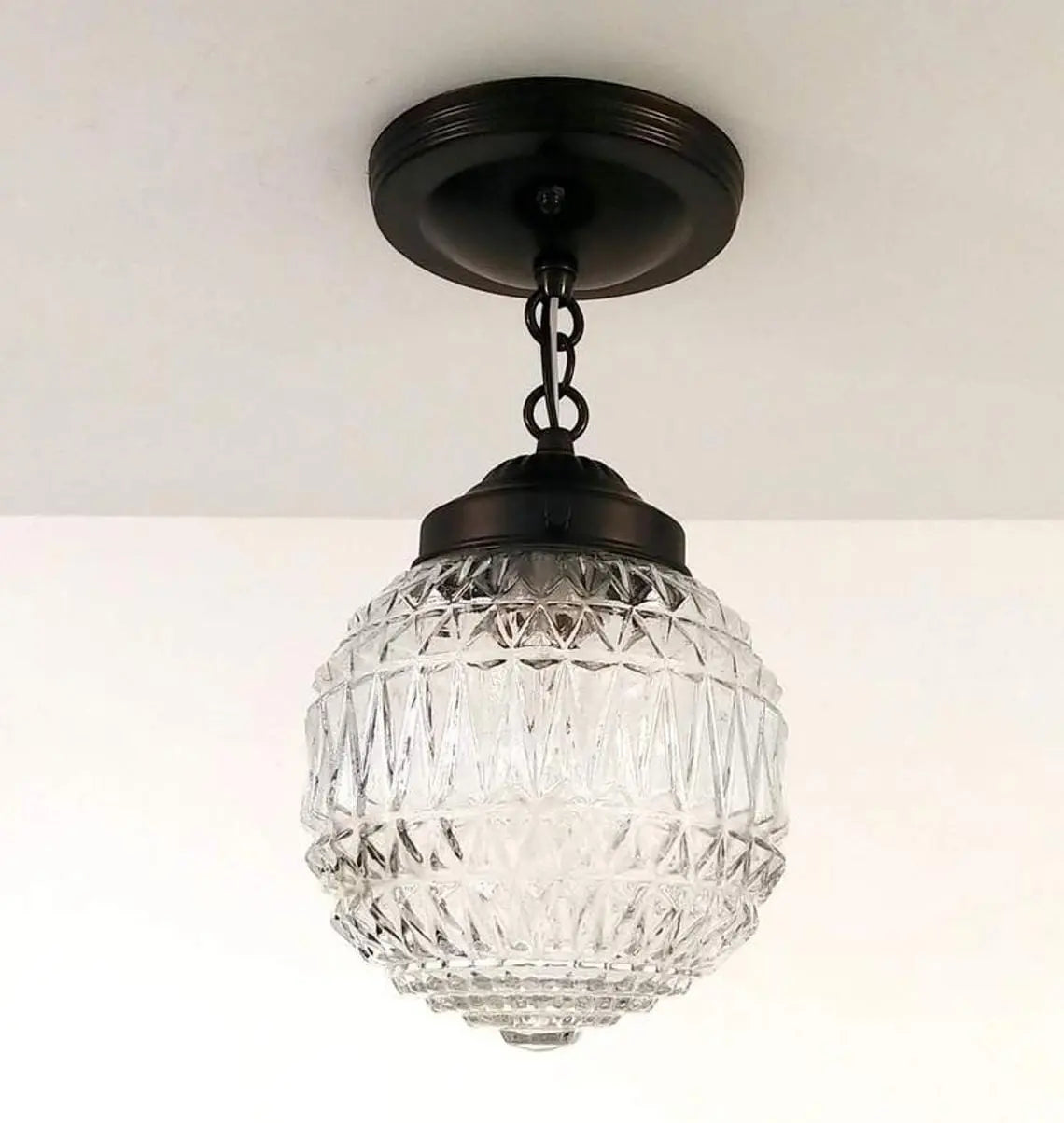 Clear glass globe pendant light fixture with a dark bronze finish and geometric pattern.
