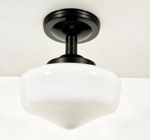 White milk glass ceiling fixture with a black metal base, installed on a white ceiling.
