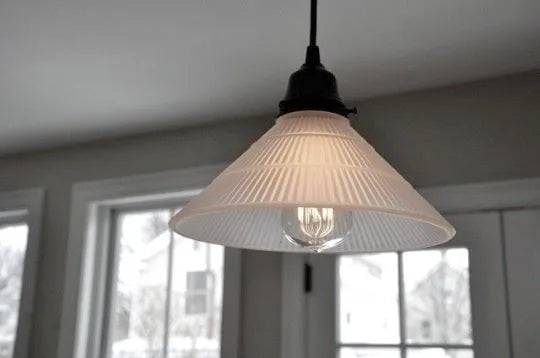 Frosted glass pendant light fixture with ribbed detailing, illuminating a room with natural light.
