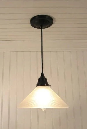 Frosted glass pendant light fixture with ribbed detailing, hanging against white paneled walls.
