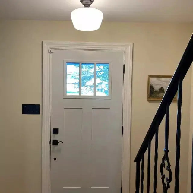 White entryway door with glass window panes, next to a dark metal staircase.
