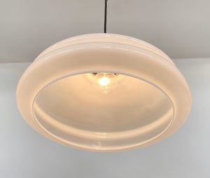 Creamy white milk glass pendant light fixture, illuminated, shown hanging from ceiling.
