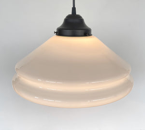 Cream-colored milk glass pendant light fixture with a black metal canopy, softly illuminated.
