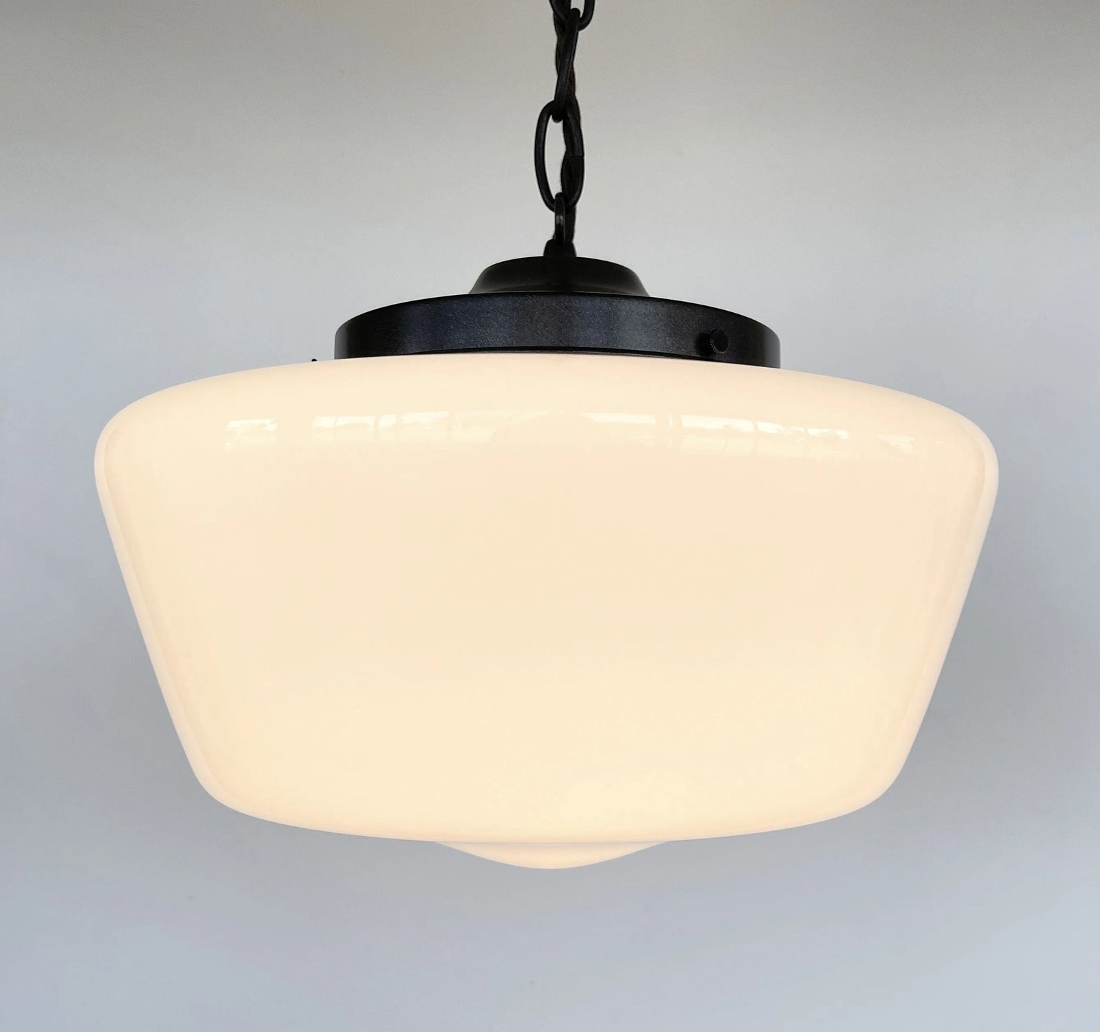Cream milk glass pendant light fixture with a dark metal frame and chain.
