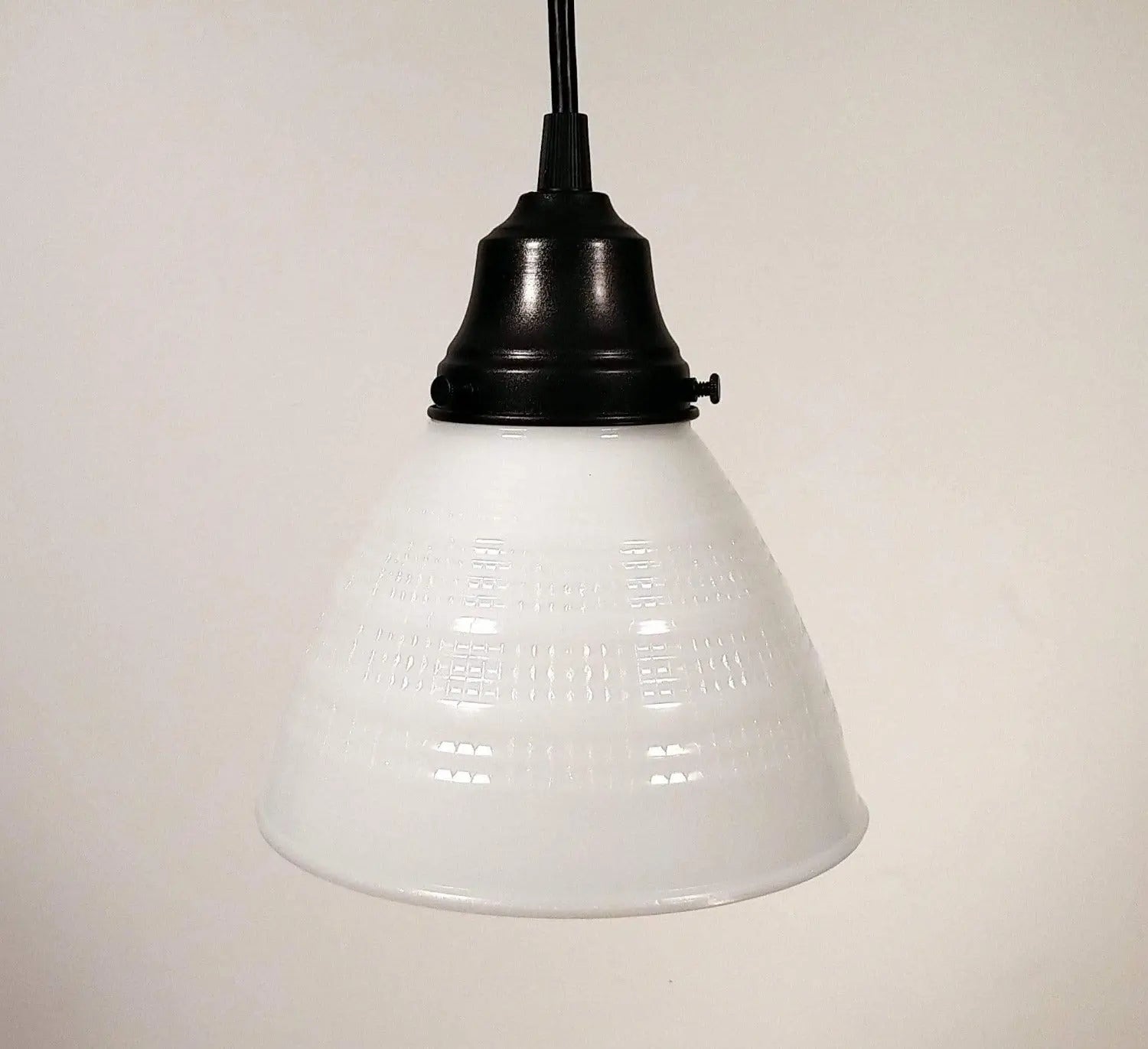 White milk glass pendant light with a waffle pattern and black metal shade.
