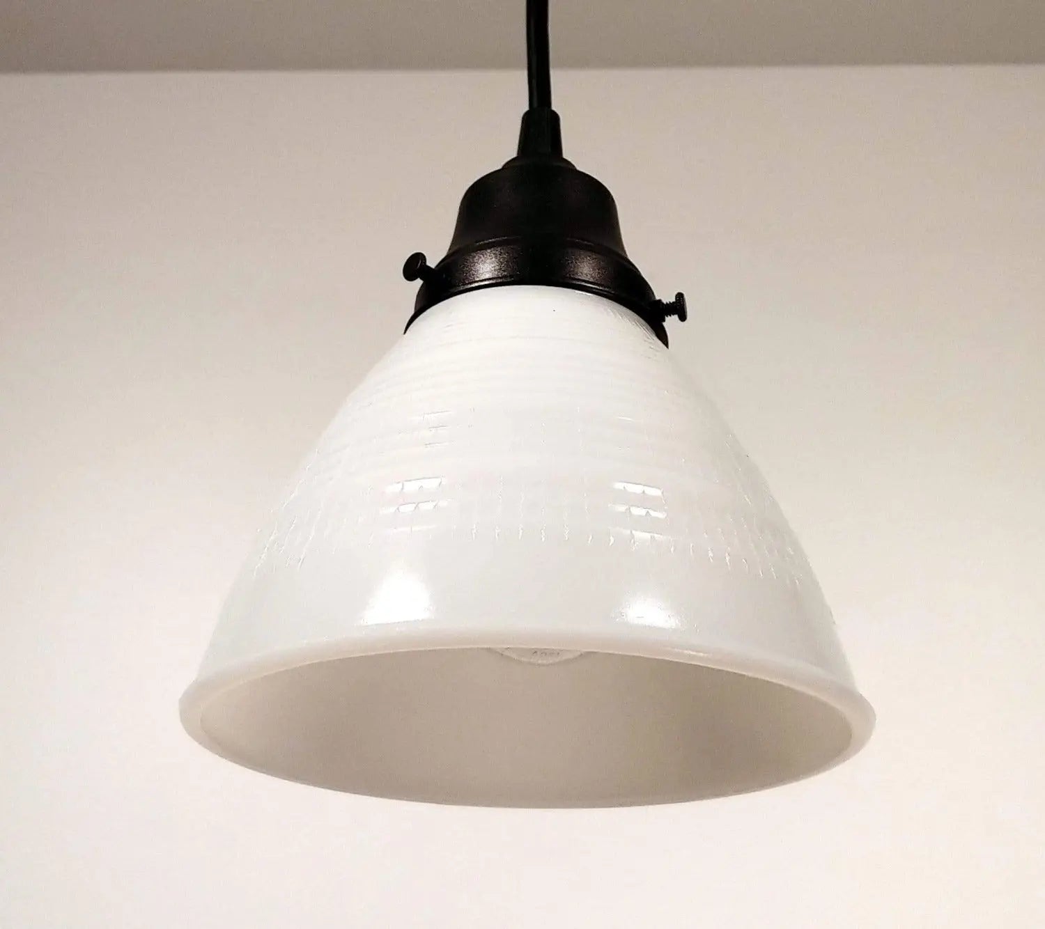 White milk glass pendant light with a waffle pattern and dark bronze fitting.
