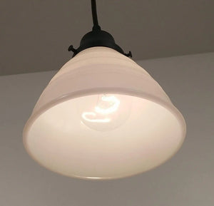 Cream-colored milk glass pendant light fixture with a waffle texture and black metal accents.
