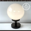 Milk glass globe table lamp with black metal base; The Lamp Goods.
