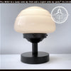 Milk glass table lamp with black metal base; The Lamp Goods.

