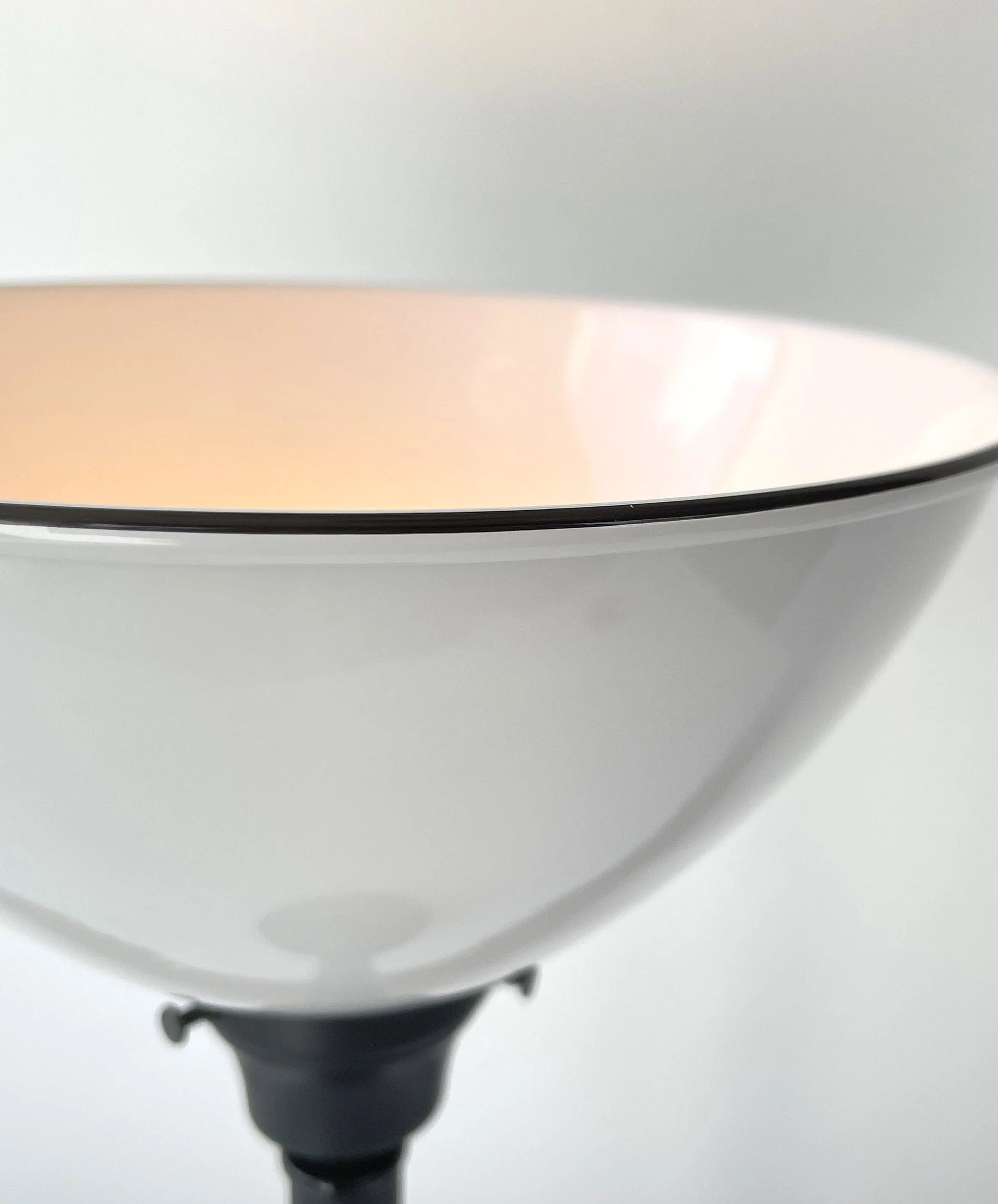 Close-up of a white lampshade with a dark rim, illuminated from within.
